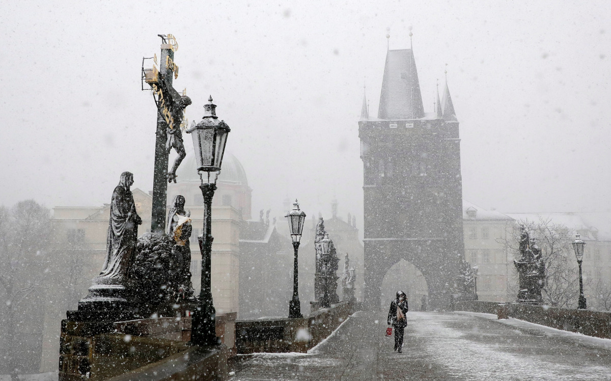 A woman walks across the medieval Charles Bridge during snowfall amid the coronavirus disease (COVID-19) outbreak in PRAGUE, Czech Republic, April 6, 2021. REUTERS/David W Cerny
