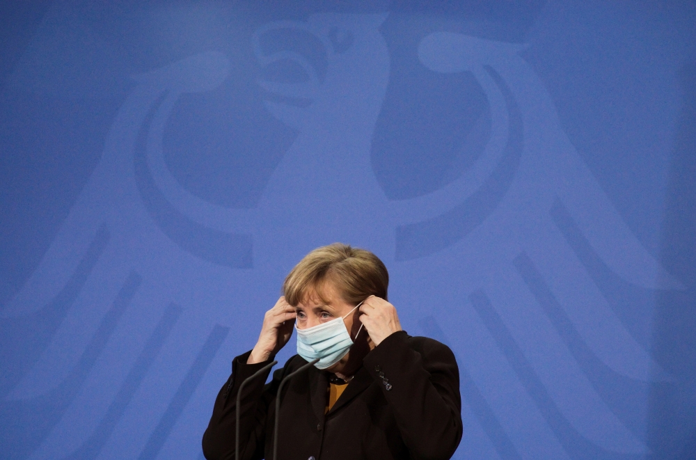 German Chancellor Angela Merkel puts on her face mask as she briefed the media after a virtual meeting with federal state governors at the chancellery in Berlin, Germany, March 30, 2021. Markus Schreiber/Pool via REUTERS/File Photo