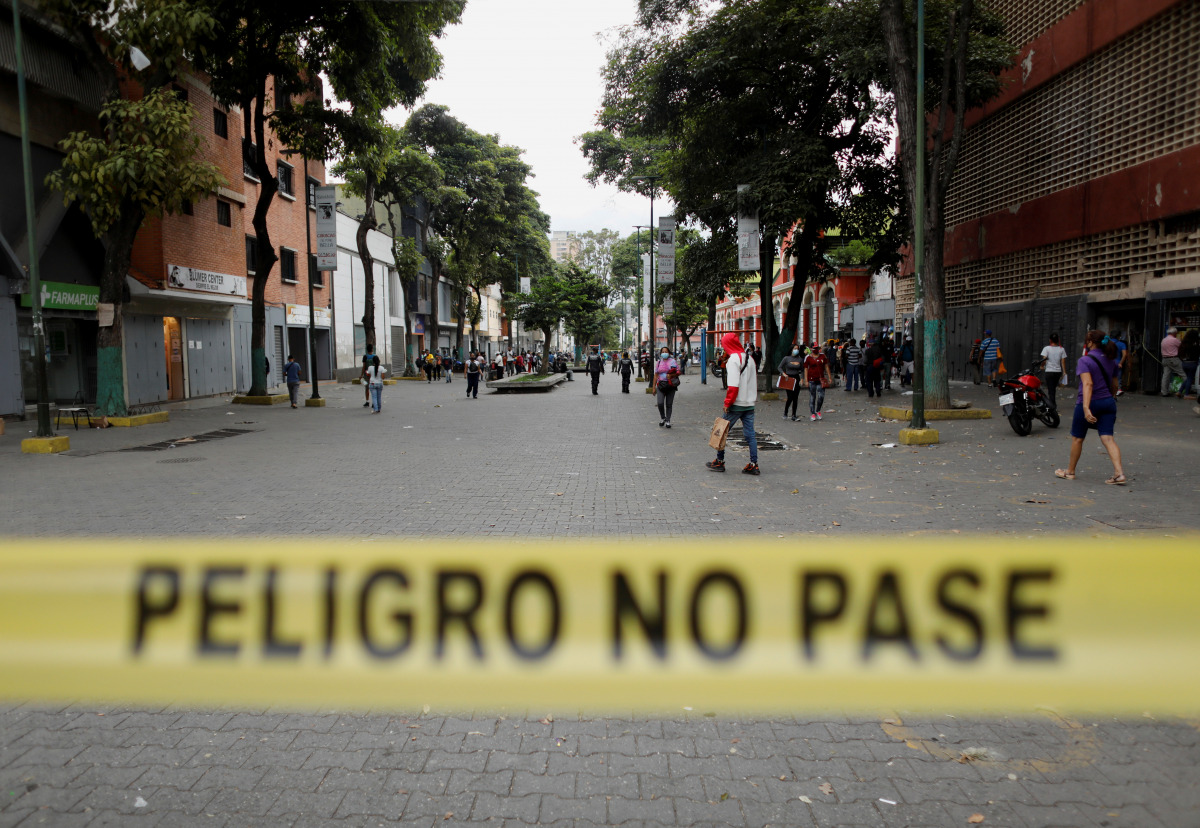 People walk behind a yellow tape reading 