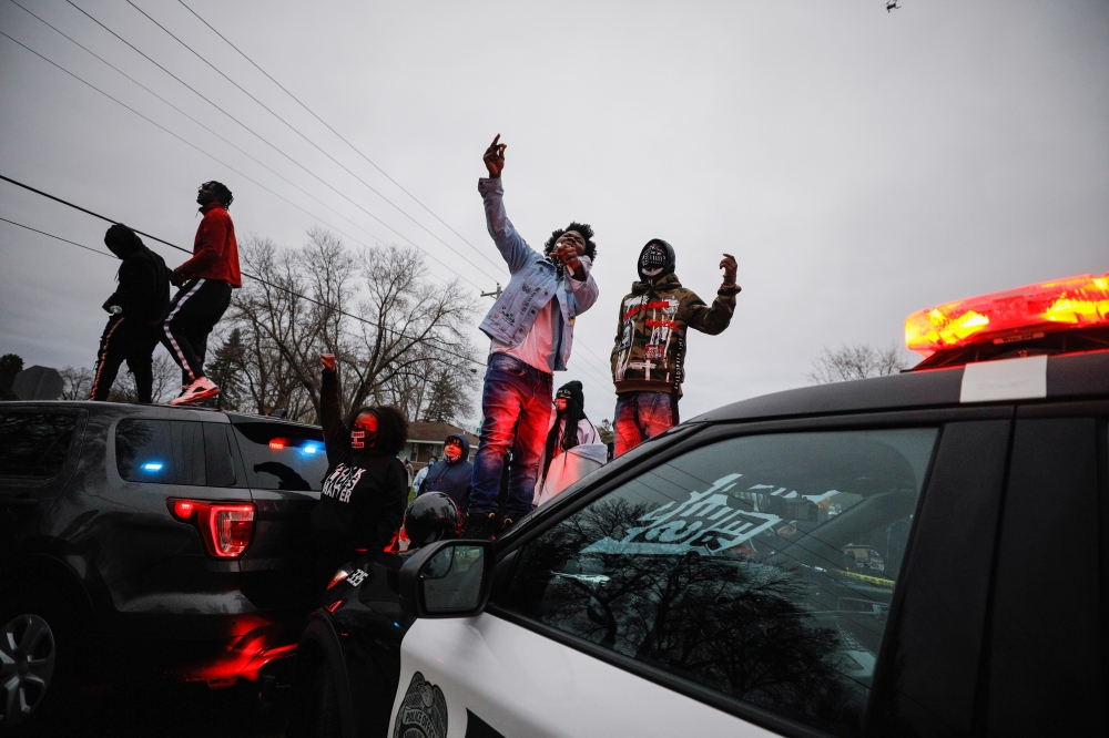 Demonstrators stand on a police vehicle during a protest after police allegedly shot and killed a man, in Brooklyn Center, Minnesota, U.S., April 11, 2021. REUTERS/Nick Pfosi
