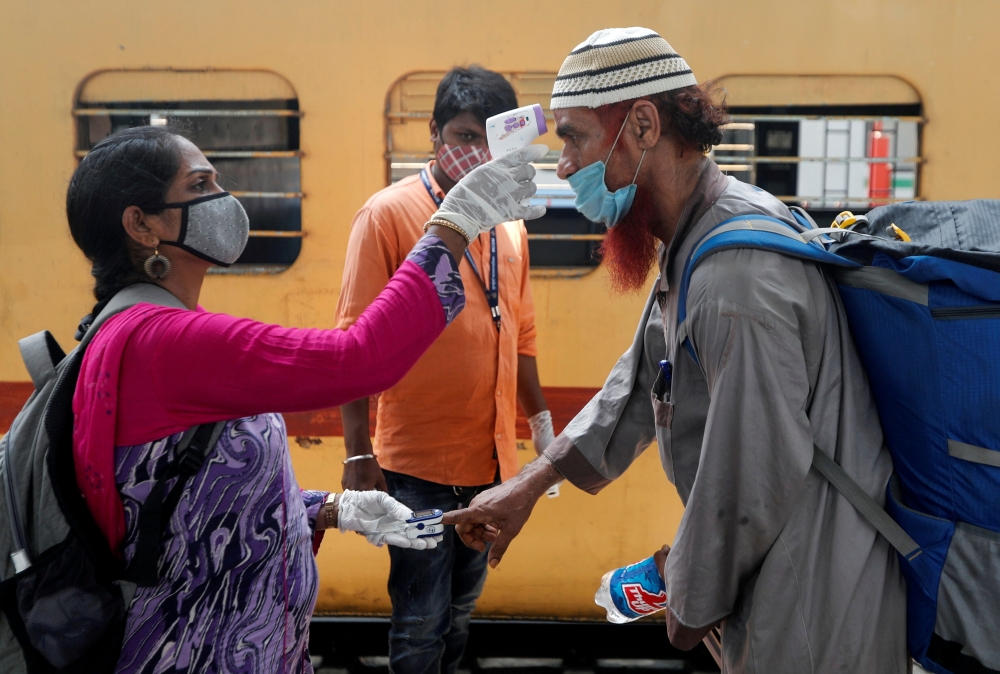 A health worker checks a passenger's temperature and pulse at a railway station platform amidst the spread of the coronavirus disease (COVID-19) in Mumbai, India, April 7, 2021. REUTERS/Francis Mascarenhas/File Photo