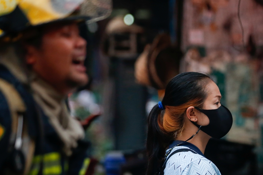 A woman wearing a protective face mask watches a fire, during the coronavirus disease (COVID-19) outbreak, in Bangkok, Thailand, April 15, 2021. REUTERS/Soe Zeya Tun