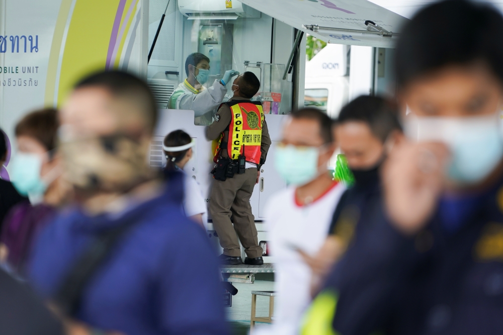 A healthcare worker takes a nasal swab sample from a police officer for a coronavirus disease (COVID-19) test, as the country deals with a fresh wave of infections after tackling earlier outbreaks, in Bangkok, Thailand April 16, 2021. REUTERS/Athit Perawo