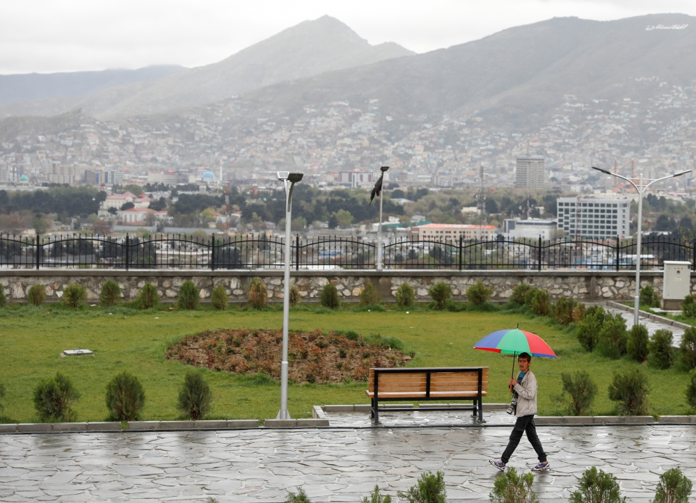 An Afghan man holds an umbrella as he walks on a rainy day on a hilltop overlooking Kabul, Afghanistan, April 15, 2021. Reuters/Mohammad Ismail