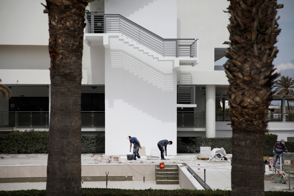 Workers wearing protective face masks put tiles on the pool area of Blue Sea Beach Resort, amid the coronavirus disease (COVID-19) pandemic, on the island of Rhodes, Greece, April 14, 2021. Picture taken April 14, 2021. REUTERS/Louiza Vradi