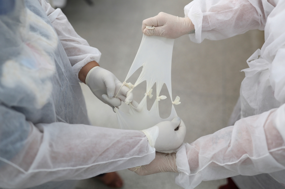 Nursing technician Semei Araujo Cunha and nurse Vanessa Fermenton tie up gloves to make what they call 'maozinha do amor' or 'hands of love', gloves filled with warm water to use on coronavirus disease (COVID-19) patients intubated at a UPA (Emergency Ser