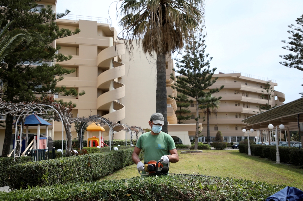 A gardener wearing a protective face mask trims a fence at the Sun Beach Resort, amid the coronavirus disease (COVID-19) pandemic, on the island of Rhodes, Greece, April 14, 2021. REUTERS/Louiza Vradi/File Photo