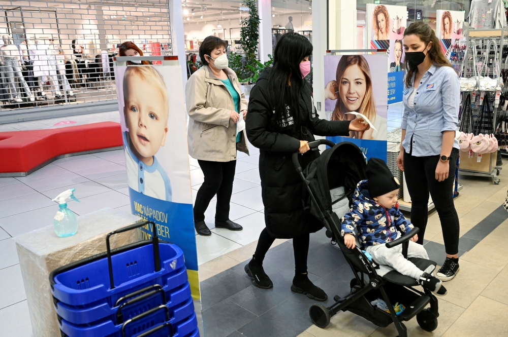 A shop assistant checks the negative COVID-19 test certificate as customers come to a store in the mall, as shops reopen after a lockdown, amid the coronavirus disease (COVID-19) pandemic in Trencin, Slovakia, April 19, 2021. REUTERS/Radovan Stoklasa/File