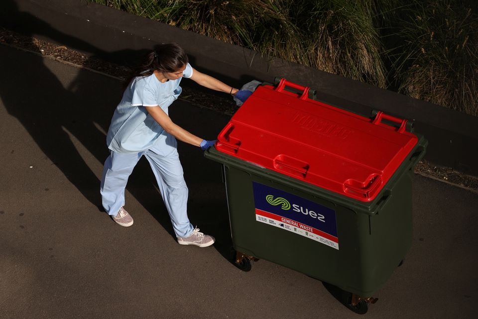 A worker disposes of waste outside a quarantine hotel where returning travelers are kept in isolation for a period to curb the spread of the coronavirus disease (COVID-19) in Sydney, Australia, August 21, 2020. REUTERS/Loren Elliott

