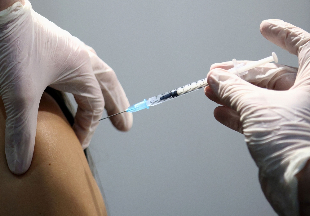 A healthcare worker receives a dose of a Pfizer-BioNTech COVID-19 vaccine at Messe Wien Congress Center, which has been set up as a coronavirus disease vaccination centre, in Vienna, Austria February 7, 2021. REUTERS/Lisi Niesner/File Photo