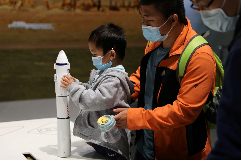 A child holds part of a rocket model at an exhibition featuring the development of China's space exploration on the country's Space Day at China Science and Technology Museum in Beijing, China April 24, 2021. REUTERS/Tingshu Wang/File Photo
