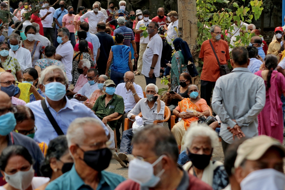 FILE PHOTO: People wearing protective face masks wait to receive a vaccine for the coronavirus disease (COVID-19) at a vaccination centre in Mumbai, India, April 26, 2021. REUTERS/Niharika Kulkarni/File Photo