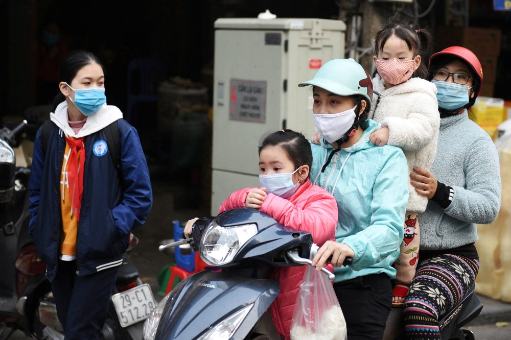 A family wears protective masks as they ride a motorbike in the street amid the coronavirus disease (COVID-19) outbreak in Hanoi, Vietnam, January 29, 2021. REUTERS/Thanh Hue/File Photo