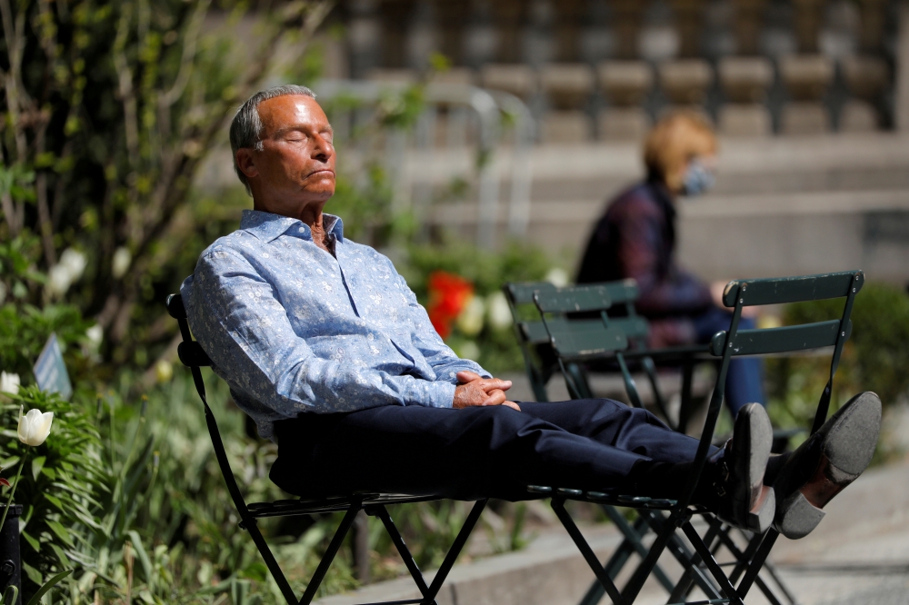 A person sits in Bryant Park after the Centers for Disease Control and Prevention (CDC) announced new guidelines regarding outdoor mask wearing and vaccination during the outbreak of the coronavirus disease (COVID-19) in Manhattan, New York City, New York
