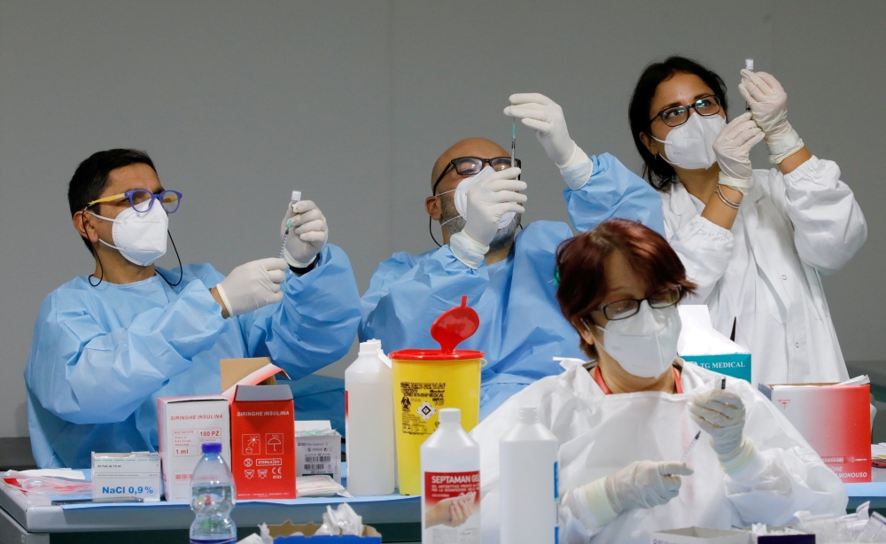Health workers prepare doses of the Pfizer-BioNTech COVID-19 vaccine at an inoculation centre in Naples, Italy, January 8, 2021. REUTERS/Ciro De Luca/File Photo