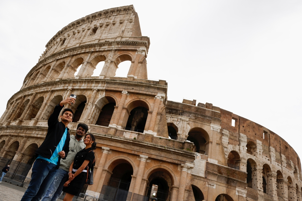 People take a selfie outside the Colosseum on the day of its reopening, as much of the country becomes a 'yellow zone', easing coronavirus disease (COVID-19) restrictions, in Rome, Italy, April 26, 2021. Reuters/Guglielmo Mangiapane