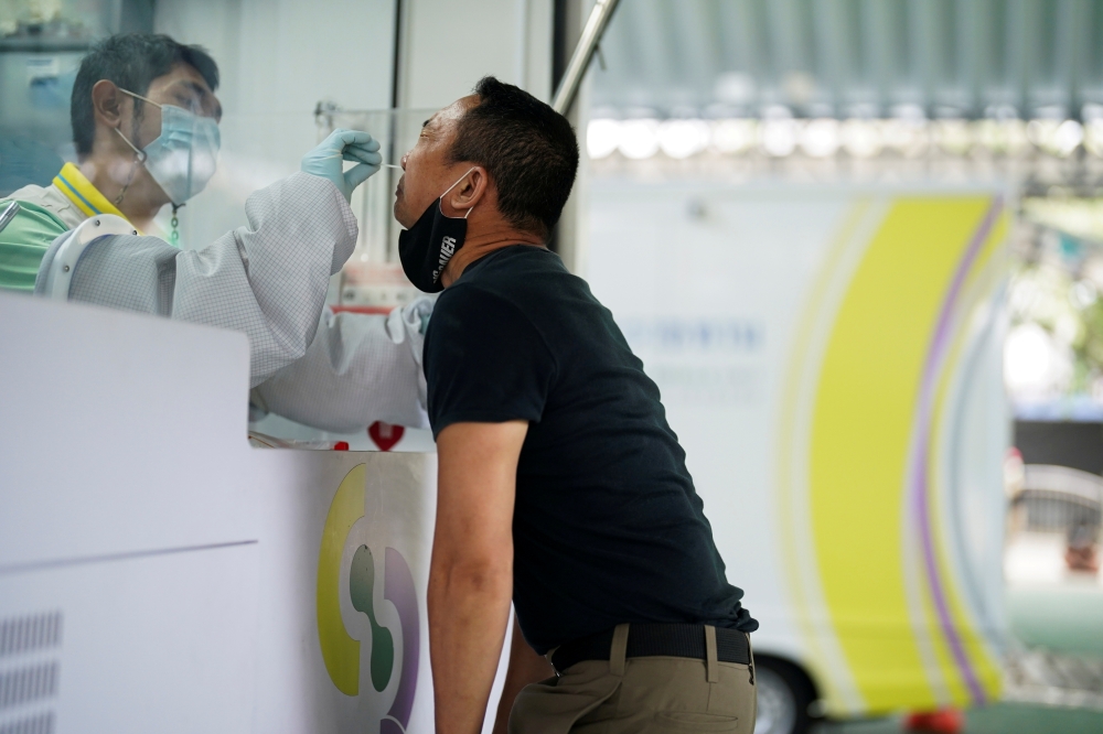 A healthcare worker takes a nasal swab sample from a person for a coronavirus disease (COVID-19) test, as the country deals with a fresh wave of infections after tackling earlier outbreaks, in Bangkok, Thailand April 16, 2021. REUTERS/Athit Perawongmetha/