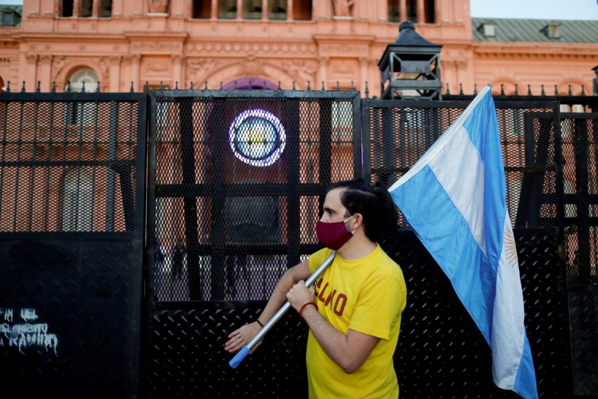 FILE PHOTO: FILE PHOTO: A demonstrator holds an Argentinian flag as they protest against Argentina's President Alberto Fernandez's lockdown measures to curb the spread of the coronavirus (COVID-19) disease, outside Casa Rosada presidential palace in Bueno