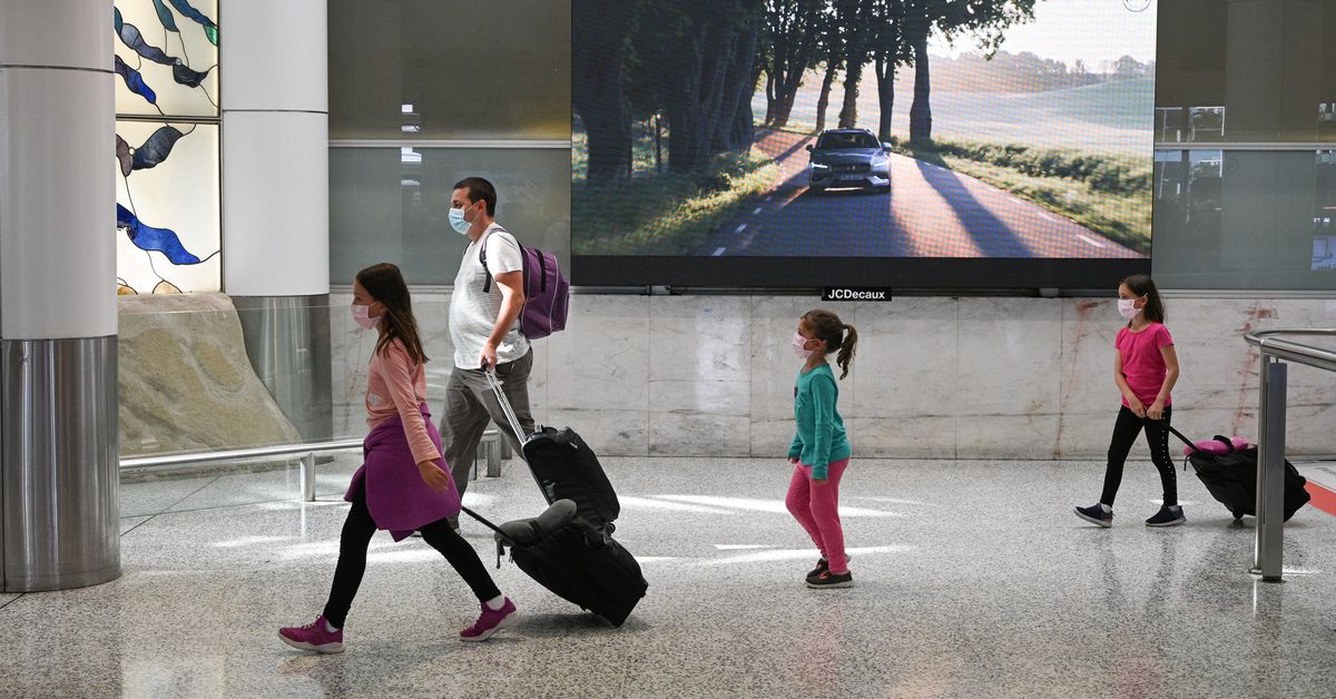 Travelers wearing protective face masks make their way through the arrivals section of the international terminal of Kingsford Smith International Airport the morning after Australia implemented an entry ban on non-citizens and non-residents intended to c