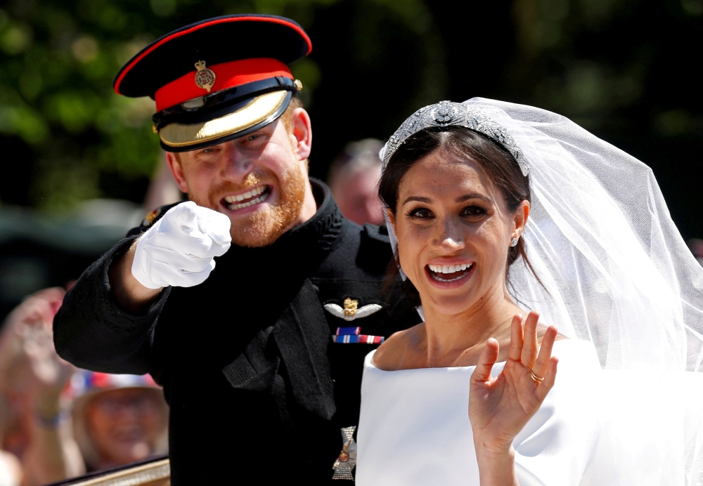 Britain’s Prince Harry gestures next to his wife Meghan as they ride a horse-drawn carriage after their wedding ceremony at St George’s Chapel in Windsor Castle in Windsor, Britain, May 19, 2018. REUTERS/Damir Sagolj/File Photo