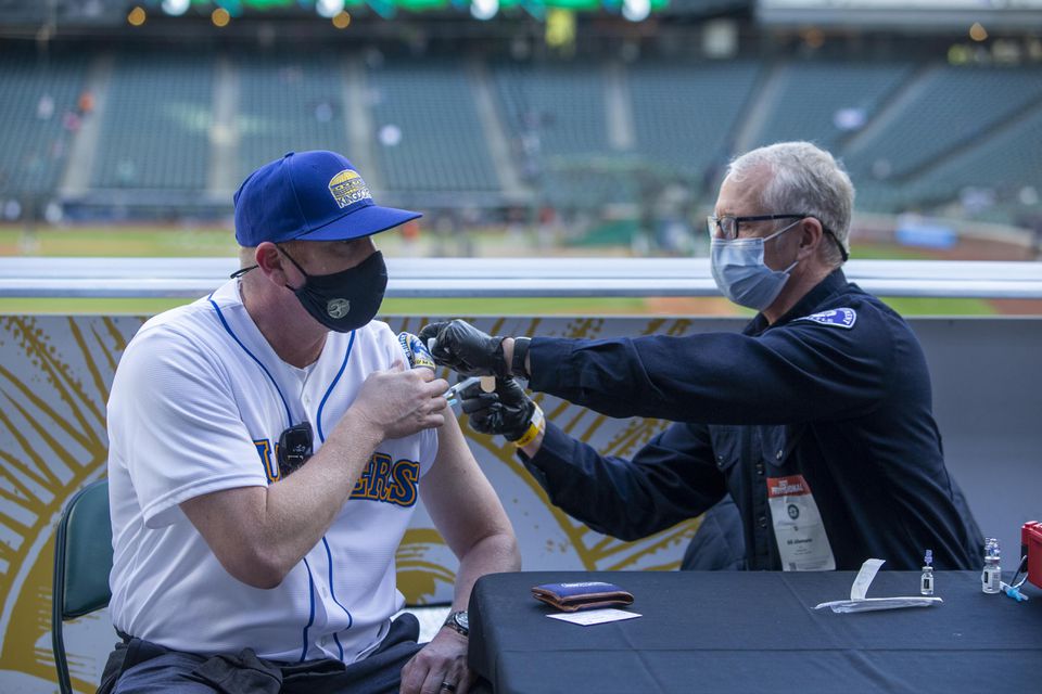 May 4, 2021; Seattle, Washington, USA; Seattle Fire Department EMT Bill Allemann gives Chris Hoffman, of Kent, Washington a Johnson & Johnson Covid-19 vaccine during batting practice before a game between the Seattle Mariners and Baltimore Orioles at T-Mo