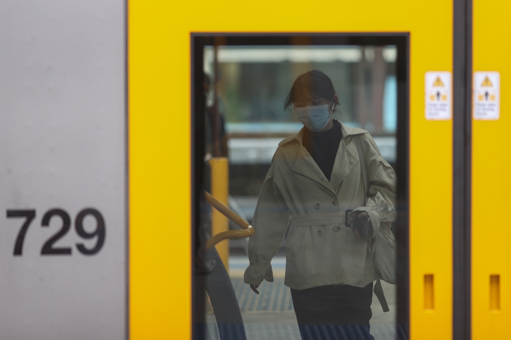 A passenger wearing a protective face mask boards a train after new public health regulations were announced for greater Sydney, including compulsory mask-wearing on public transport, following the emergence of new cases of the coronavirus disease (COVID-