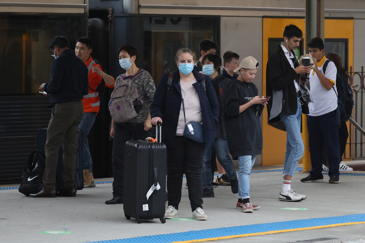 People, some wearing protective face masks, stand on a train platform at Central Station after new public health regulations were announced for greater Sydney, including compulsory mask-wearing on public transport, following the emergence of new cases of 