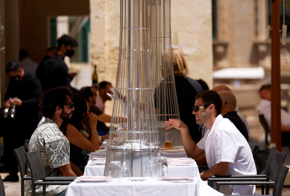 People sit at an outdoor patio as restaurants and markets reopened for business after coronavirus disease (COVID-19) vaccinations reached 60% of the adult population, in Valletta, Malta May 10, 2021. REUTERS/Darrin Zammit Lupi