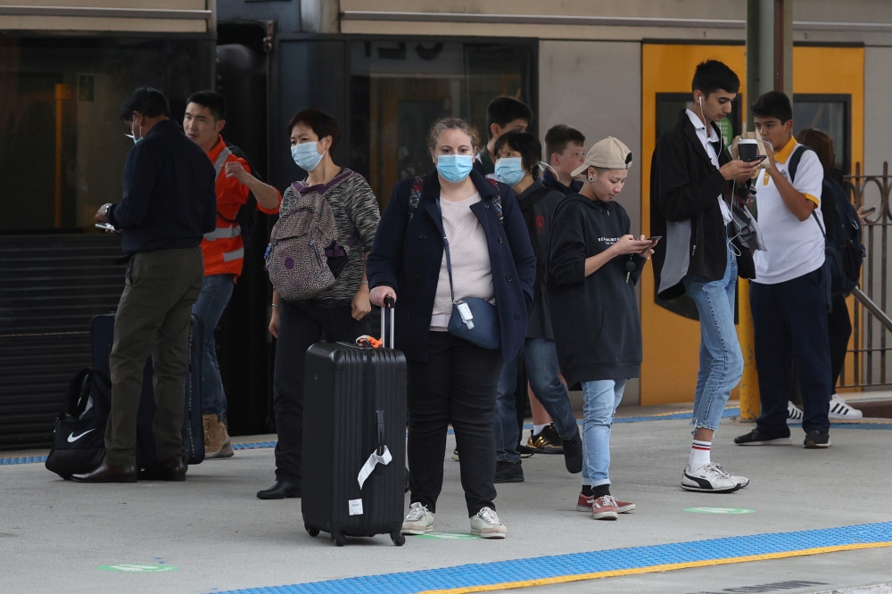 People, some wearing protective face masks, stand on a train platform at Central Station after new public health regulations were announced for greater Sydney, including compulsory mask-wearing on public transport, following the emergence of new cases of 