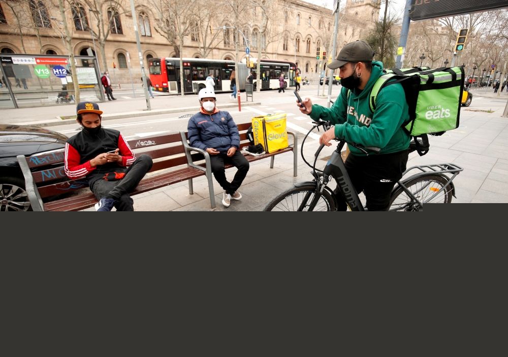 Delivery riders with backpacks wait for orders at Universitat square in Barcelona, Spain. (REUTERS/Albert Gea/File Photo)