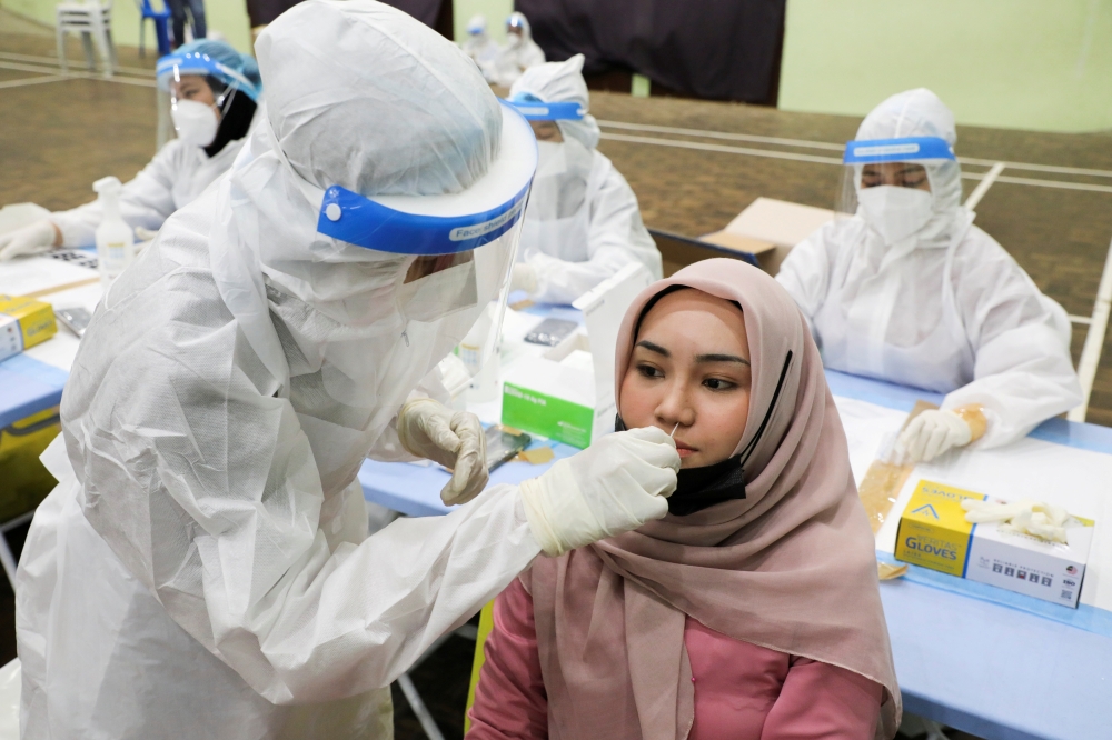  A medical worker collects a swab sample from a woman to be tested for the coronavirus disease (COVID-19) in Kuala Lumpur, Malaysia, May 11, 2021. REUTERS/Lim Huey Teng/File Photo