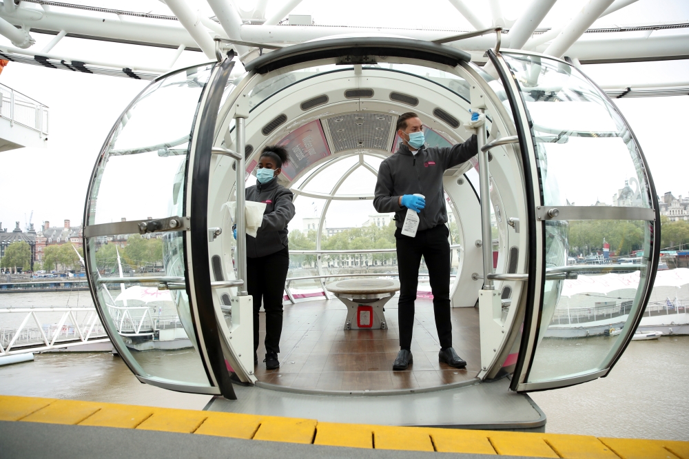 Hosts clean a pod of London Eye in preparation to reopen as coronavirus disease (COVID-19) restrictions continue to ease, in London, Britain, May 14, 2021. REUTERS/Peter Cziborra