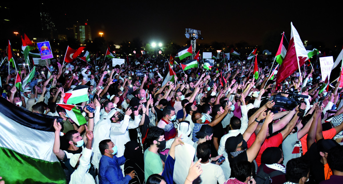 People wave Palestinian and Qatari flags during a rally to express solidarity with Palestinians, in Doha, yesterday. Pic: Abdul Basit / The Peninsula 
