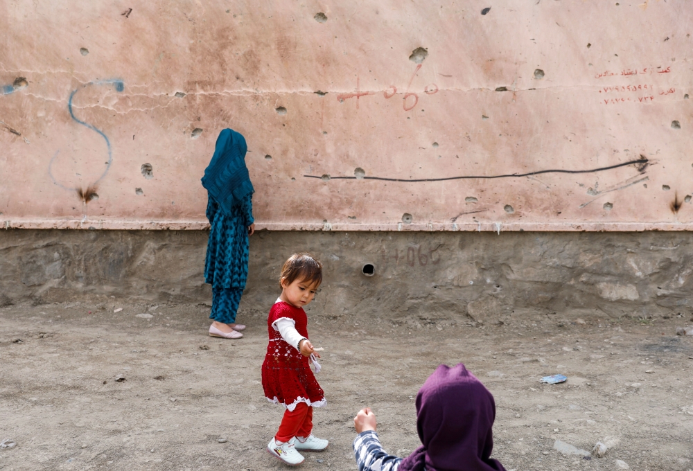 Children stand next to a damaged wall at the site of a car bomb blast in Kabul, Afghanistan May 10, 2021. REUTERS/Stringer/File Photo