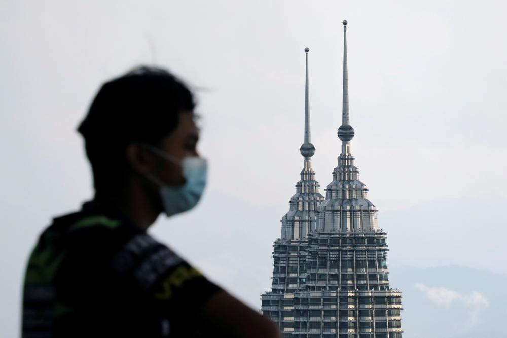 A man wearing a protective mask looks on as the Petronas Twin Towers are seen in the background, amid the the coronavirus disease (COVID-19) pandemic, in Kuala Lumpur, Malaysia April 12, 2021. REUTERS/Lim Huey Teng/File Photo