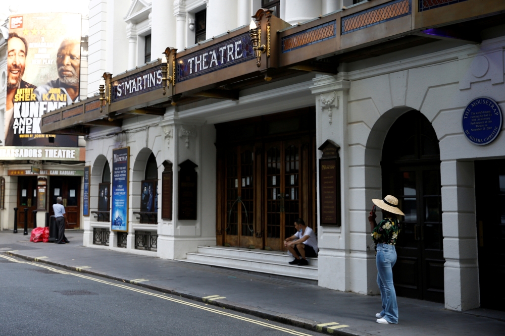 People stand next to St Martin's Theatre at London's West End in London, Britain, August 13, 2020. REUTERS/Henry Nicholls/File Photo