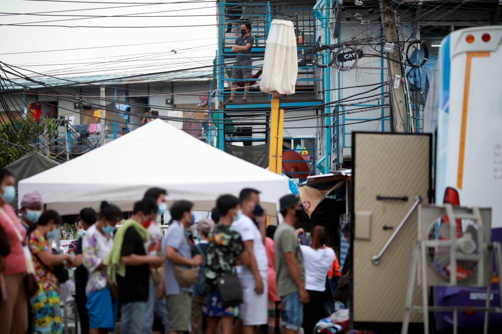 A man stands outside his apartment as people who have tested positive for the coronavirus disease (COVID-19) wait for paperwork to be processed by authorities before they are sent to a hospital, in Bangkok, Thailand May 17, 2021. REUTERS/Soe Zeya Tun