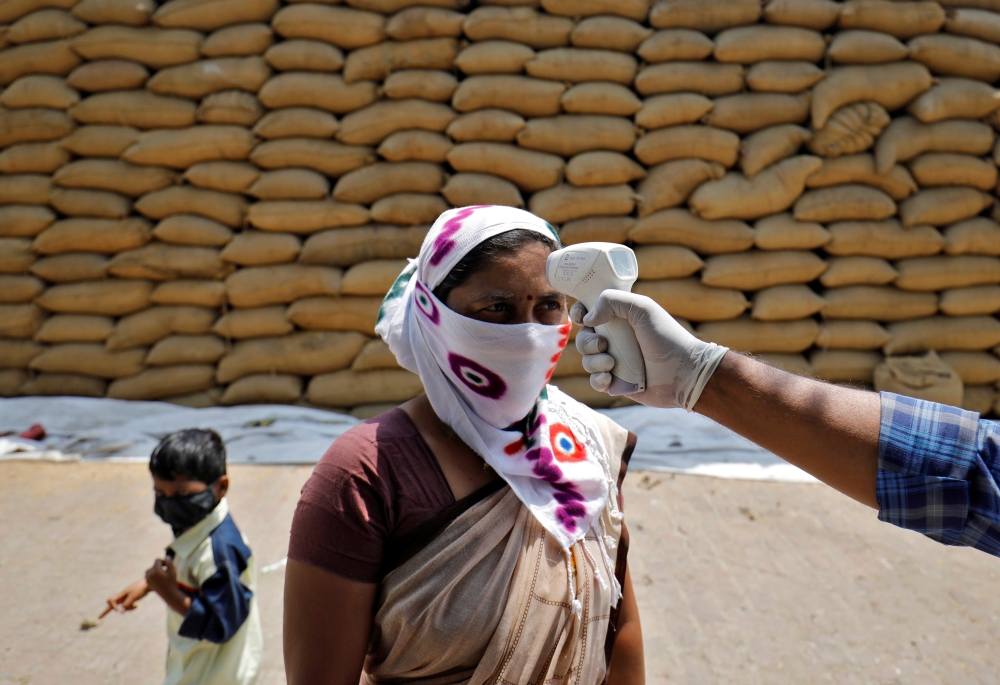 File photo: A healthcare worker checks the temperature of a rice mill worker during a coronavirus disease (COVID-19) vaccination drive at Bavla village on the outskirts of Ahmedabad, India, April 13, 2021. Reuters/Amit Dave/File Photo