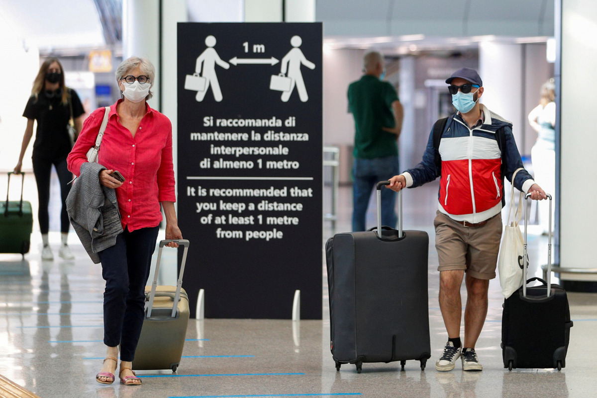 FILE PHOTO: Passengers wearing protective face masks walk at Fiumicino Airport on the day EU governments agreed a 