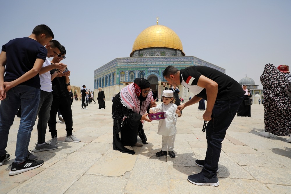 A Palestinian woman offers sweets to a boy before Friday prayer at the compound that houses Al-Aqsa Mosque REUTERS/Ammar Awad