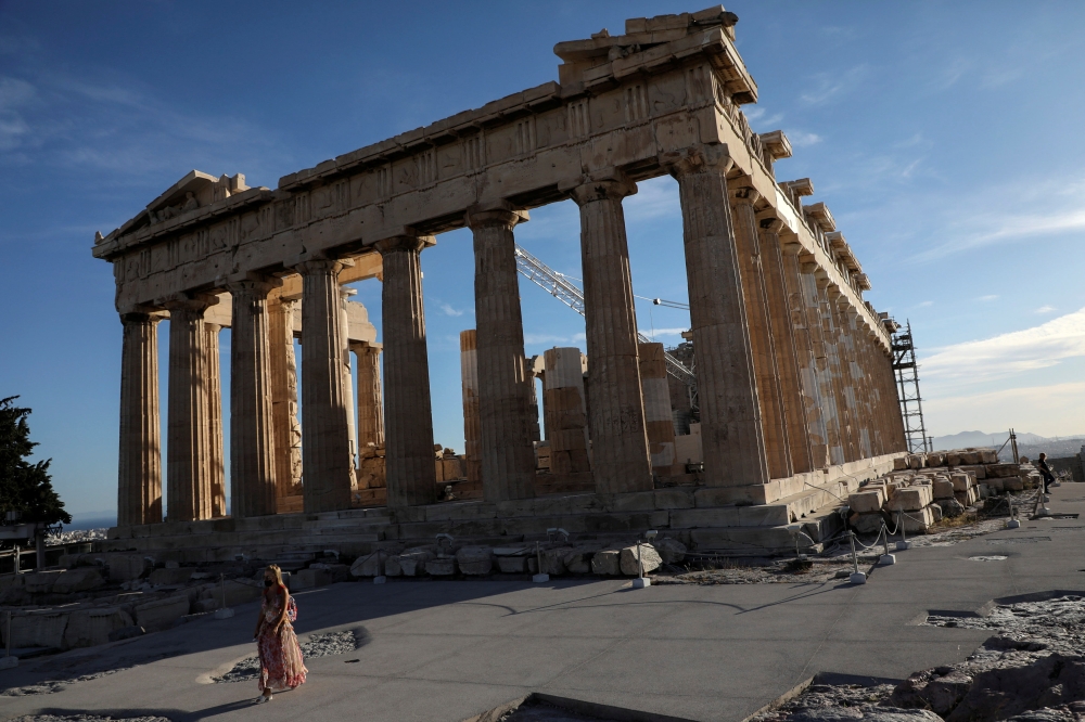 A woman wearing a protective face mask walks by the Parthenon temple atop the Acropolis hill in Athens, Greece, May 17, 2021. Reuters/Louiza Vradi