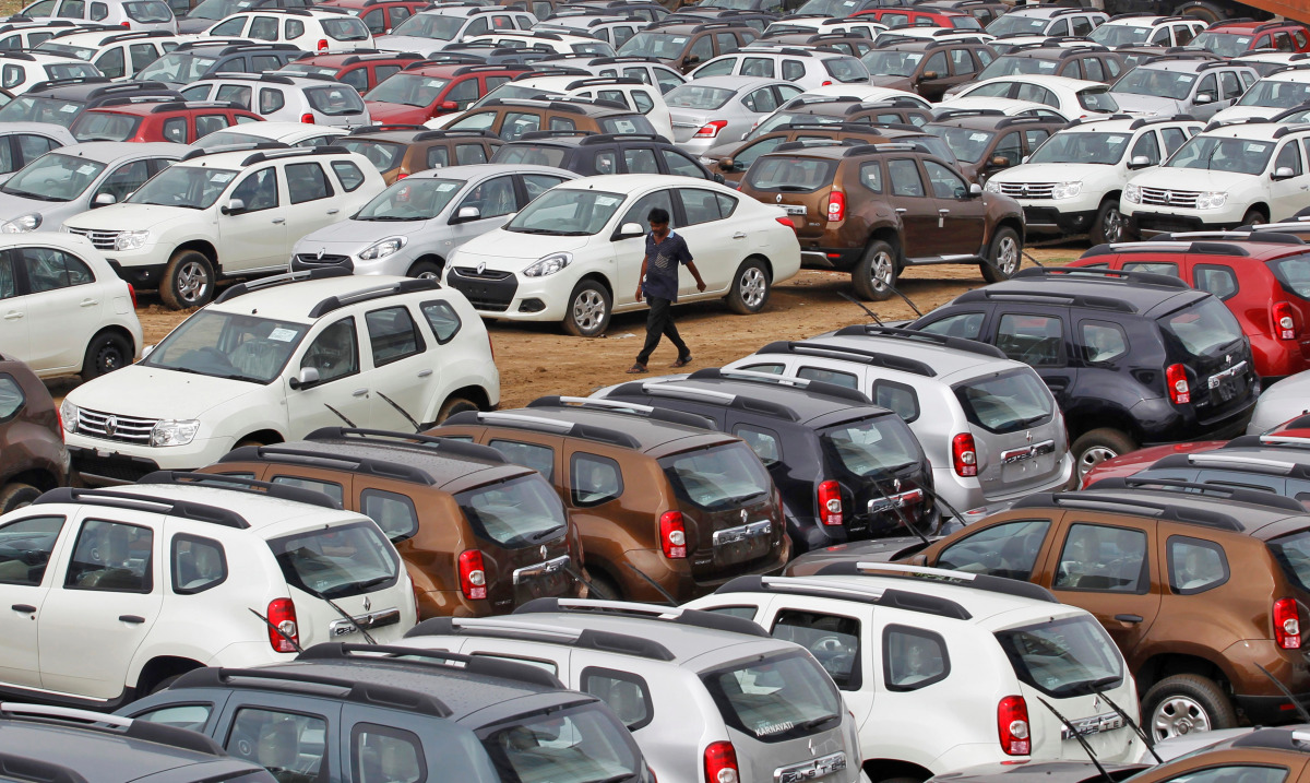 FILE PHOTO: A worker walks past parked Renault cars at its stockyard on the outskirts of the western Indian city of Ahmedabad June 11, 2013. Car sales in India fell an annual 12.3 percent in May, an industry body said on Tuesday, dropping for the seventh 