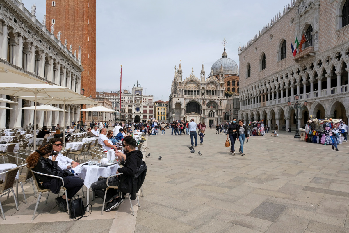 FILE PHOTO: People sit at outdoor tables at St. Mark's Square as Italy lifts quarantine restrictions for travellers arriving from European Union countries, Britain and Israel and begins offering COVID-free flights in a bid to revive the tourism industry, 