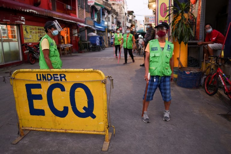 Local officials wearing face masks and face shields as protection against the coronavirus disease (COVID-19) stand near a community quarantine checkpoint in a village under local lockdown, in Pasay, Metro Manila, Philippines, February 25, 2021. REUTERS/Li