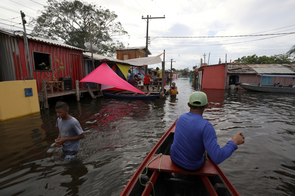 A man paddles his canoe through the streets during flooding by the overflowing Negro river at Cacau Pirera neighborhood in Iranduba, Amazonas state, Brazil, May 31, 2021. REUTERS/Bruno Kelly