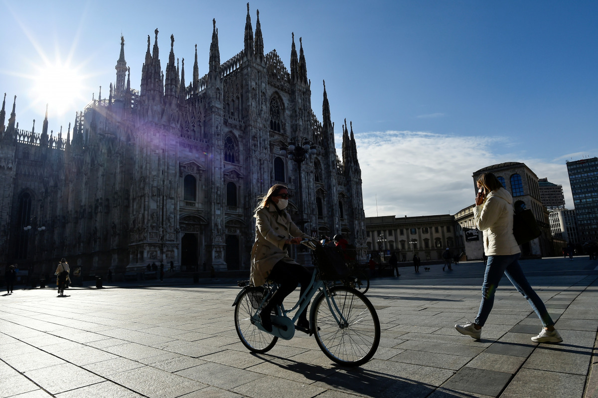 FILE PHOTO: People passes by the Duomo Cathedral, after Lombardy was downgraded from a red to an orange zone, loosening the coronavirus disease (COVID-19) restrictions including allowing non-essential shops to re-open, in Milan, Italy, April 13, 2021. REU