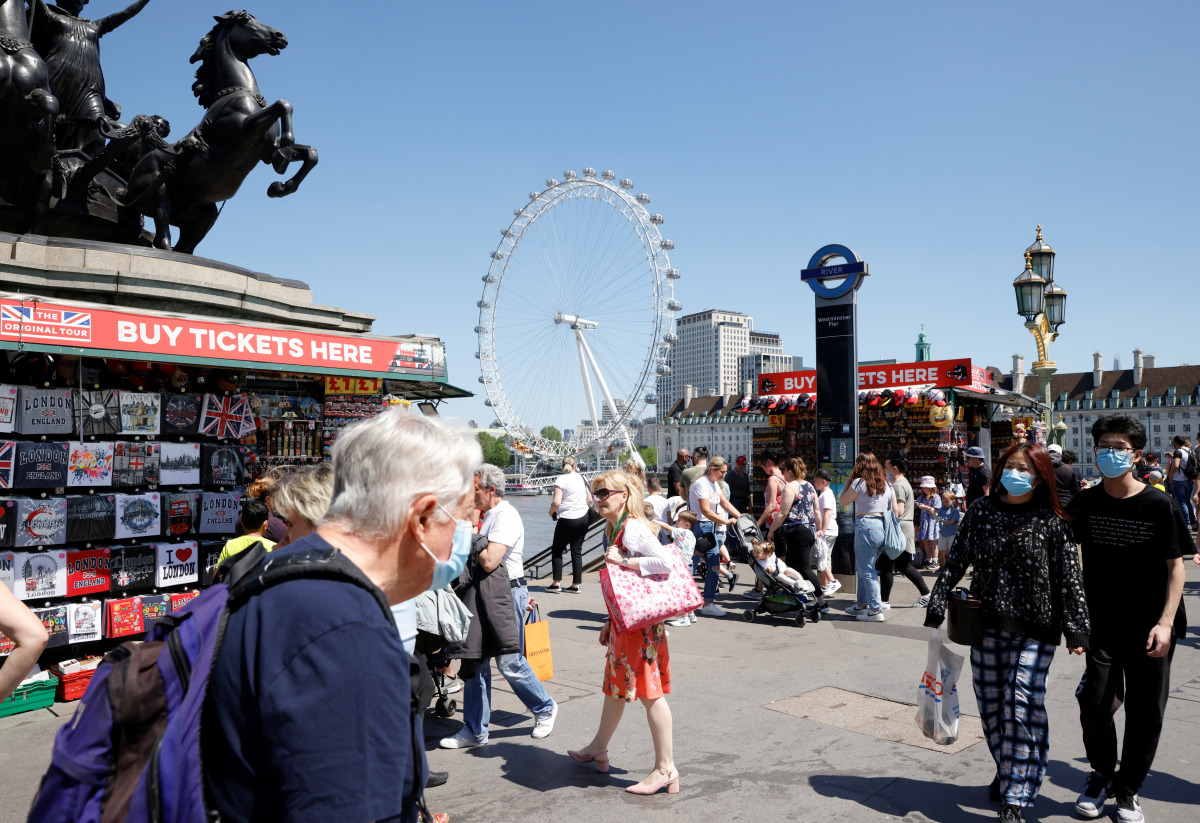 People wearing protective masks walk on Westminster Bridge, with the London Eye in the background, in London, Britain, June 1, 2021. REUTERS/John Sibley
