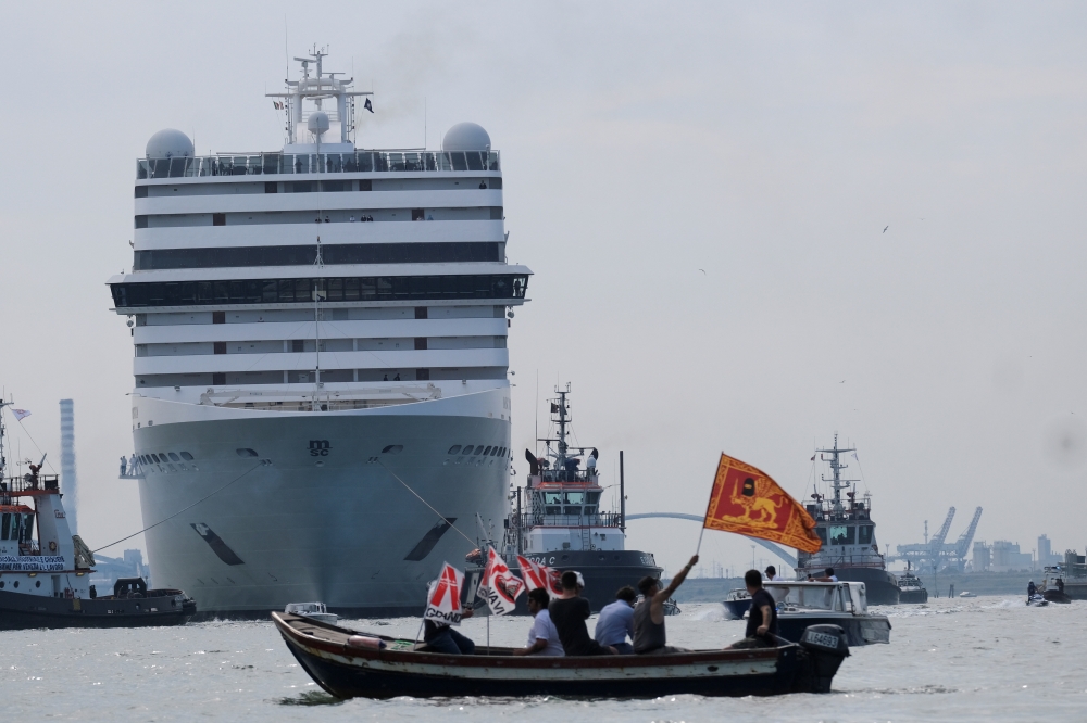 Venice residents ride on a boat as they protest to demand an end to cruise ships passing through the lagoon city, as the first cruise ship of the summer season departs from the Port of Venice, Italy, June 5, 2021. REUTERS/Manuel Silvestri