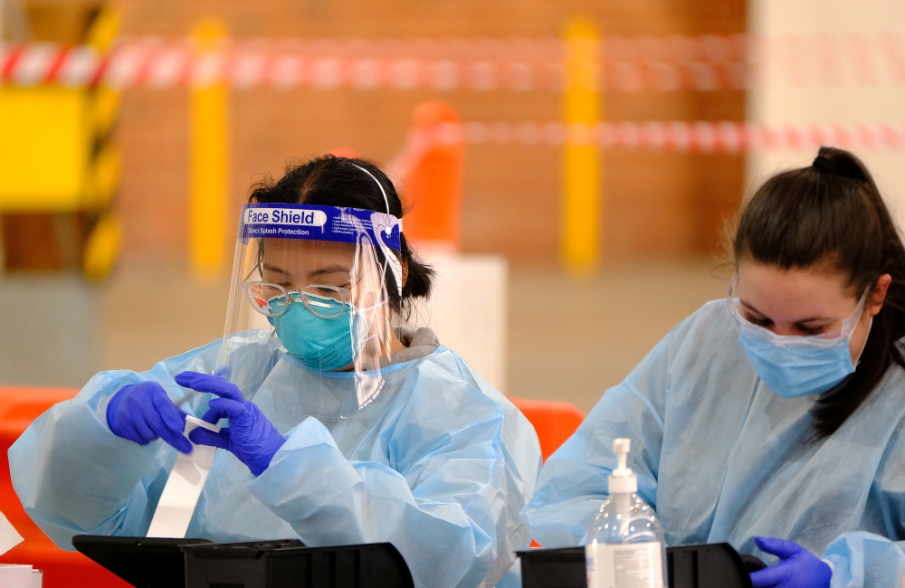 Health workers are seen at work at a drive-through coronavirus disease (COVID-19) testing facility in Melbourne, Australia, June 7, 2021. AAP Image/Luis Ascui via REUTERS