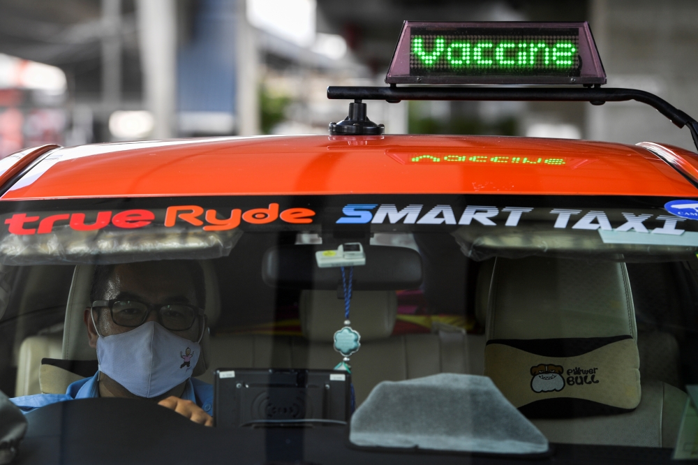 Thai taxi driver Sombat Subin rides with a sign above his cab showing that he has been vaccinated against the coronavirus disease (COVID-19) in order to attract more customers in Bangkok, Thailand, May 29, 2021. Picture taken May 29, 2021. REUTERS/Chaline